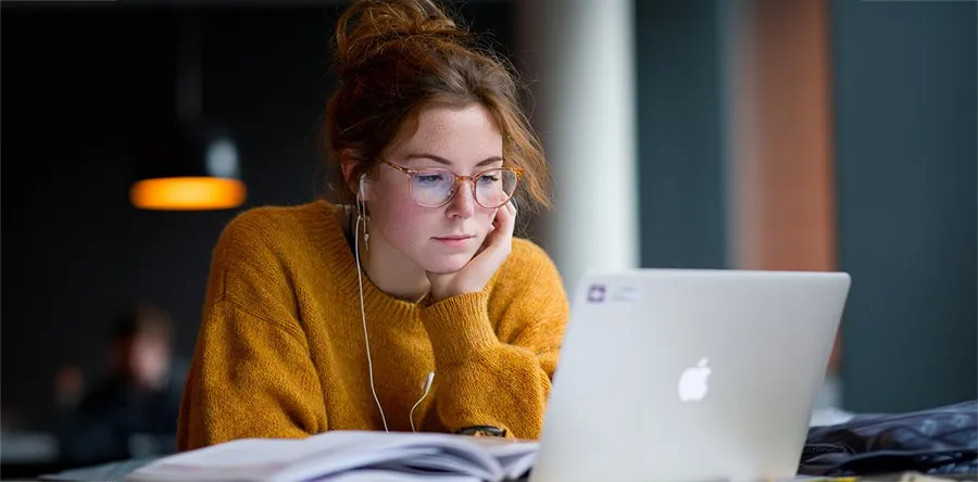 A student in front of a laptop studying online
